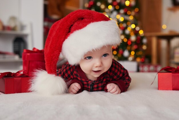 Niño de Navidad con gorro de Papá Noel en el fondo del árbol de Navidad con regalos.