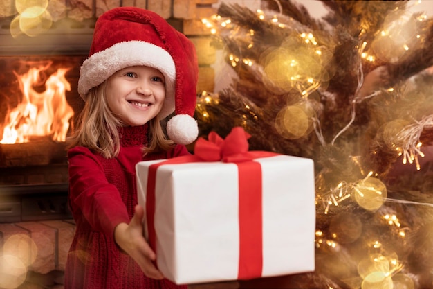 Niño de Navidad con sombrero de Santa Dar caja de regalo de Navidad en fondo de Navidad con luz de árbol de año nuevo