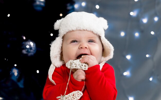 Niño de Navidad sonríe y sostiene una guirnalda con corazones.