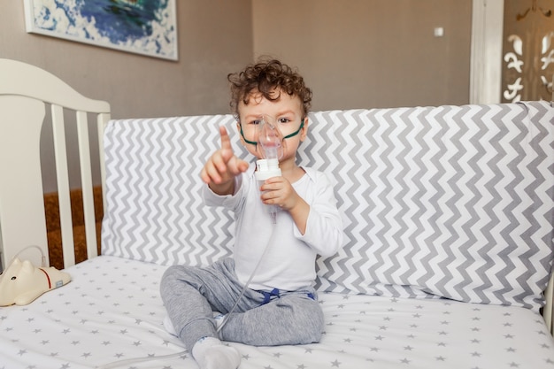 Niño con un nebulizador en la cuna.