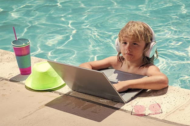 Niño de negocios de verano a distancia trabajando en portátil en la piscina pequeño hombre de negocios trabajando en línea en portátil