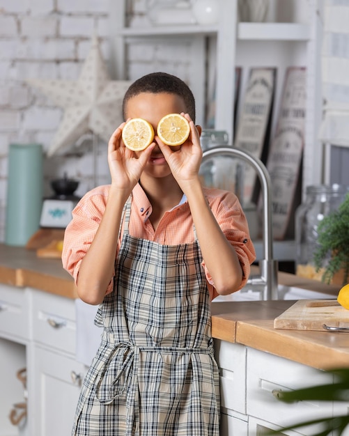 Niño negro cocinando limón fresco en la cocina en casa niño africano muestra ojos de mandarina