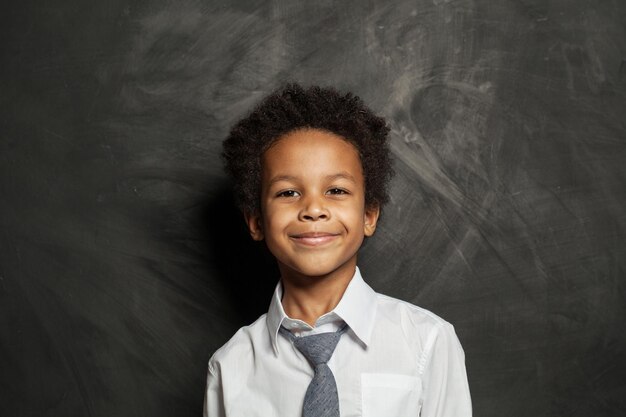 Un niño negro feliz, un niño lindo en el retrato de fondo de la pizarra.