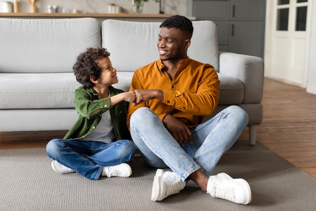 Niño negro golpeando a su padre en un momento alegre en la sala de estar