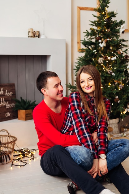 Niño y niña en una acogedora habitación con un árbol de Navidad