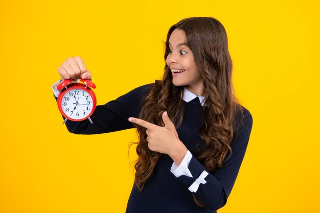 Niño niña adolescente con reloj despertador aislado sobre fondo amarillo Concepto de tiempo y fecha límite