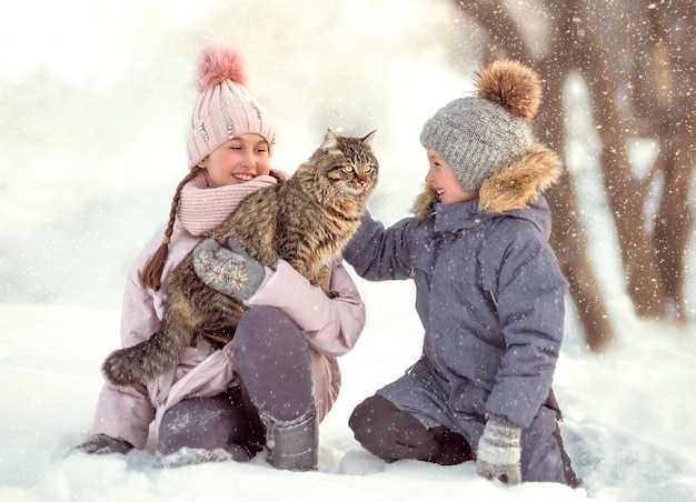 niño y niña alegre juego feliz con gato esponjoso en la calle