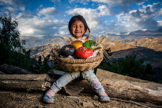 Niño y niña andina con panes de colores en el paisaje de la sierra peruana