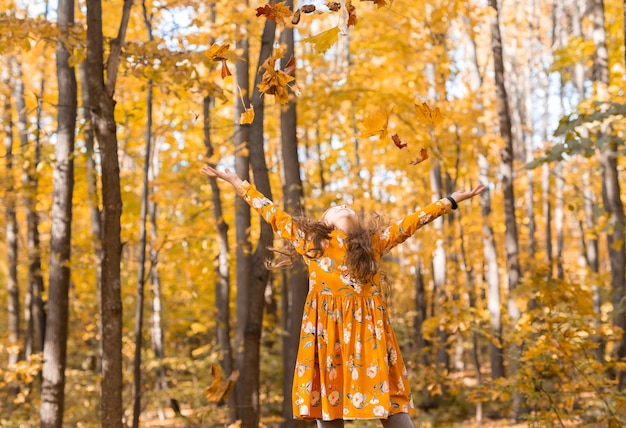 Niño niña arrojando hojas de otoño en otoño naturaleza diversión ocio y concepto de infancia