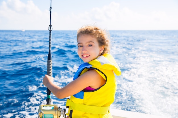 niño niña barco de pesca carrete de caña de pescar y amarillo chaleco salvavidas