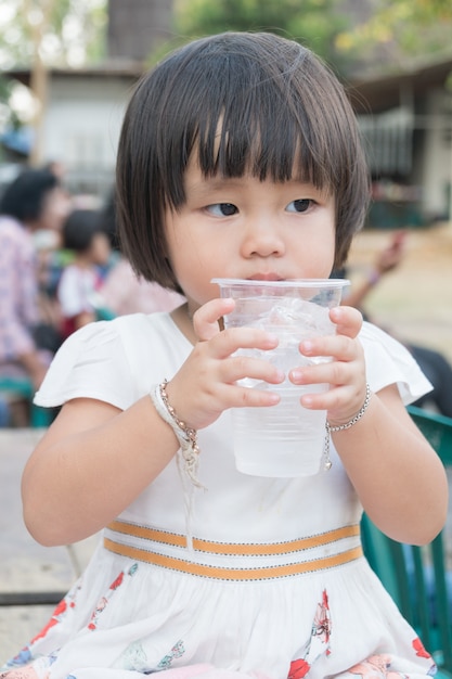 Niño niña bebiendo agua en vidrio plástico