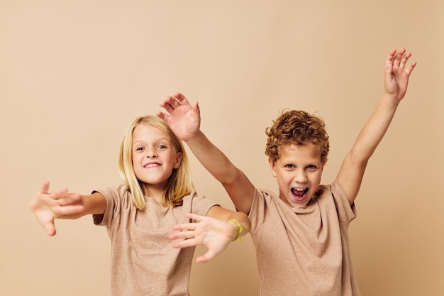 Niño y niña en camisetas beige posando para la diversión de la infancia inalterada