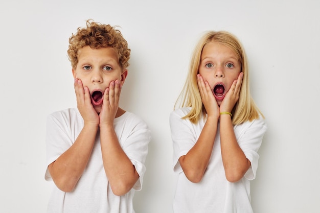 Niño y niña en camisetas blancas están de pie junto a un fondo aislado