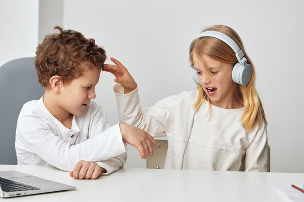 Un niño y una niña caucásicos felices estudiando juntos en casa con computadoras portátiles, aprendizaje electrónico y tecnología.