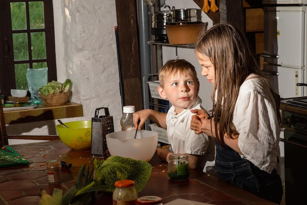 Niño y niña cocinando en la cocina foto real