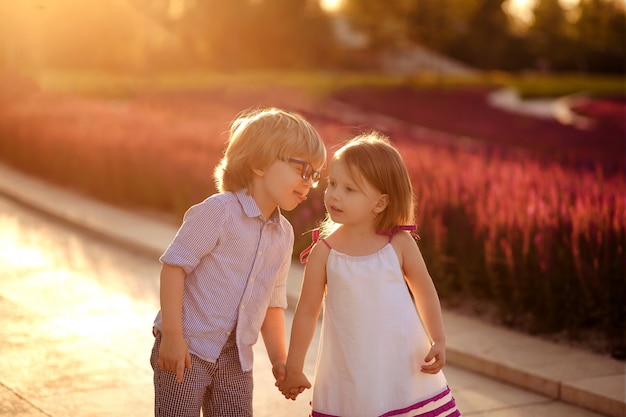 Niño y niña cogidos de la mano al atardecer