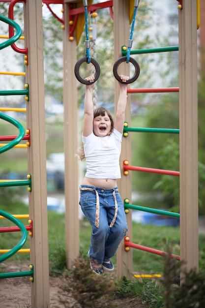 Foto niño niña colgando de los anillos en el parque infantil