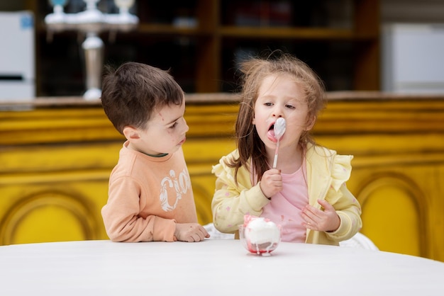 Un niño y una niña comiendo helado con una cuchara.
