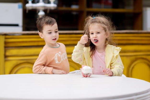 Un niño y una niña comiendo helado en una mesa