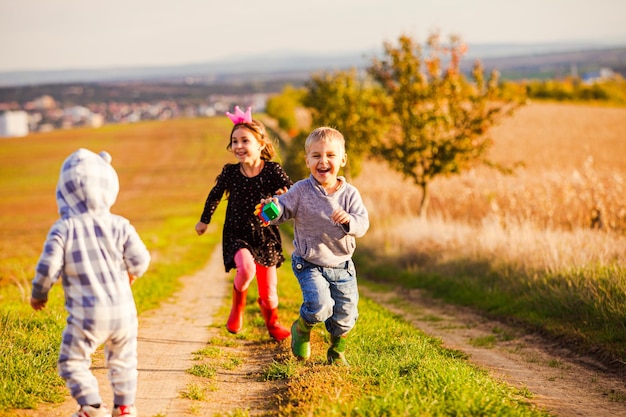 Niño y niña corriendo hacia un niño pequeño en un camino rural