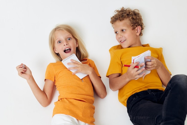 Niño y niña dibujando en cuadernos tirados en el suelo estilo de vida infantil inalterado