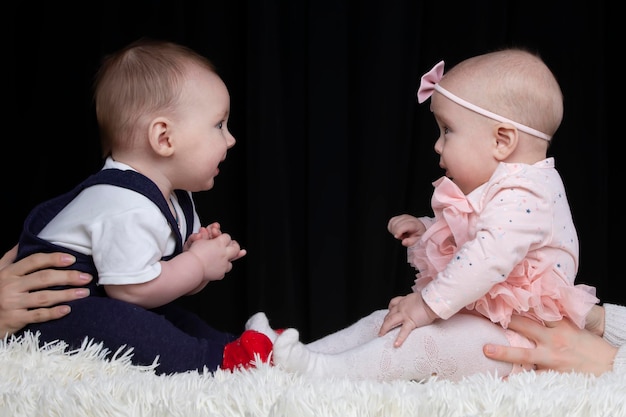 Niño y niña divertidos están sentados uno frente al otro