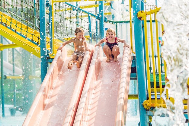 Niño y niña se divierten en el parque acuático.