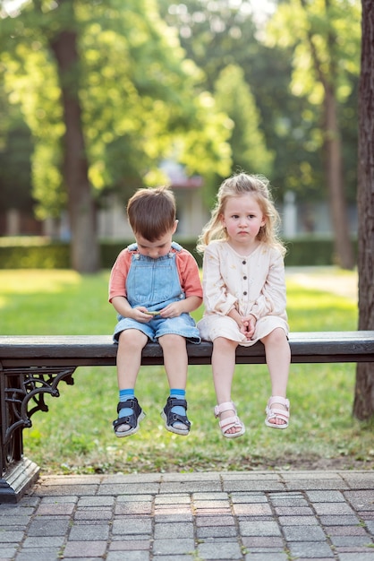 Un niño y una niña están sentados en un banco en el parque.Una niña besa a un niño en la mejilla.