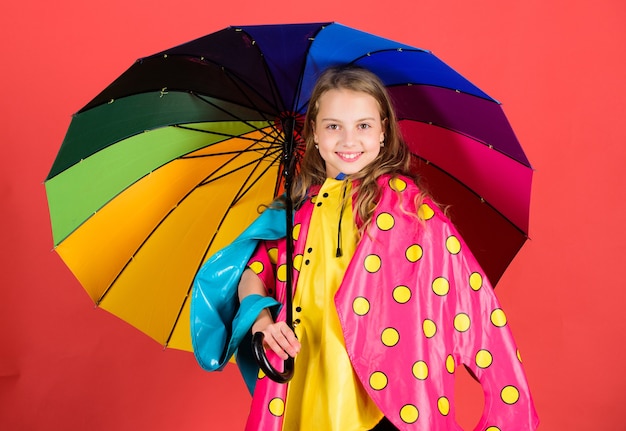 Niño niña feliz mantenga colorido paraguas usar capa impermeable. Disfrute del clima lluvioso con la ropa adecuada. Fabricación de accesorios impermeables. Los accesorios impermeables hacen que los días de lluvia sean alegres y agradables.