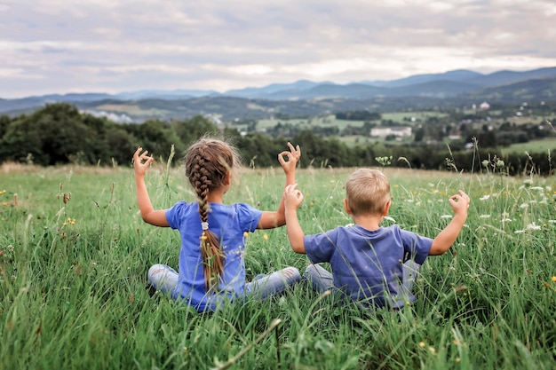 niño y niña haciendo los ejercicios matinales en la cima de las montañas