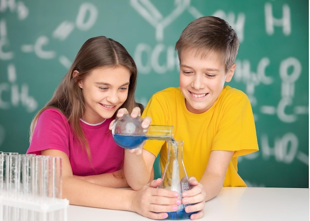 Niño y niña haciendo experimentos químicos. verter líquido en el vaso de precipitados