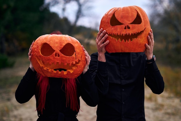 Niño y niña de halloween con calabazas en la cabeza