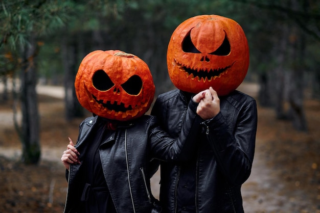 Niño y niña de halloween con calabazas en la cabeza