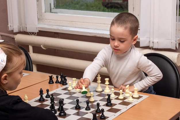 Foto un niño y una niña juegan al ajedrez el niño gana