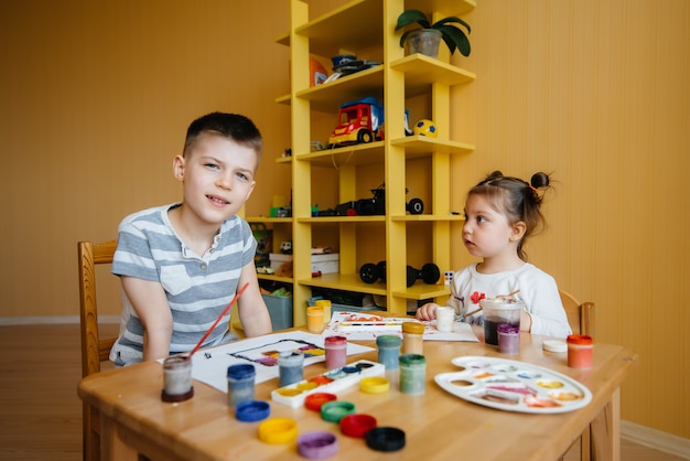 Un niño y una niña juegan juntos y pintan. Recreación y entretenimiento. Quédate en casa.