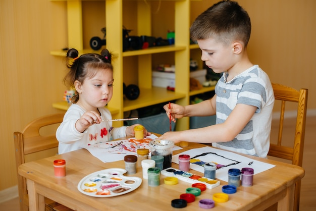 Un niño y una niña juegan juntos y pintan. Recreación y entretenimiento. Quédate en casa.