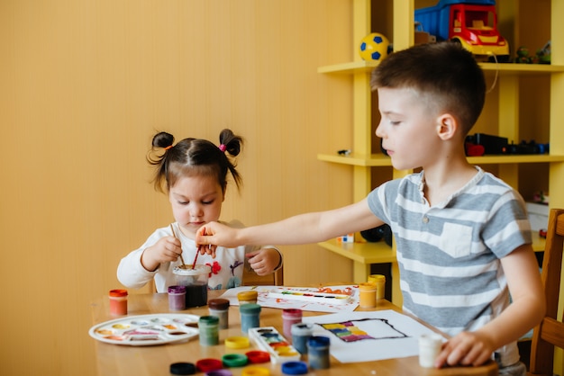 Un niño y una niña juegan juntos y pintan. Recreación y entretenimiento. Quédate en casa.