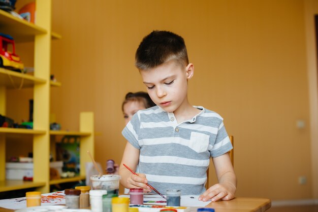 Un niño y una niña juegan juntos y pintan. Recreación y entretenimiento. Quédate en casa.