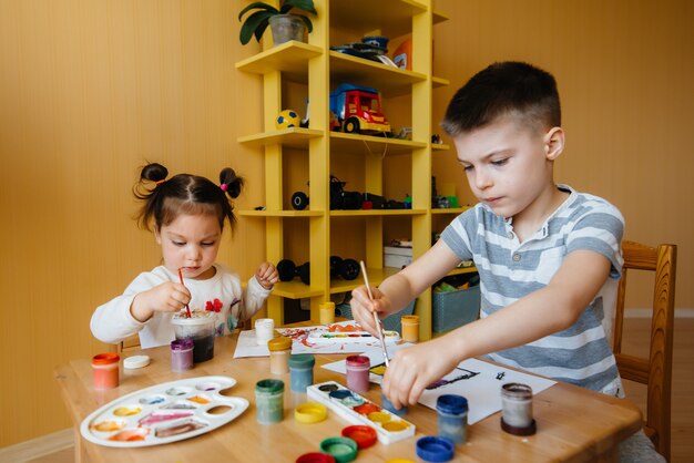 Un niño y una niña juegan juntos y pintan. Recreación y entretenimiento. Quédate en casa.