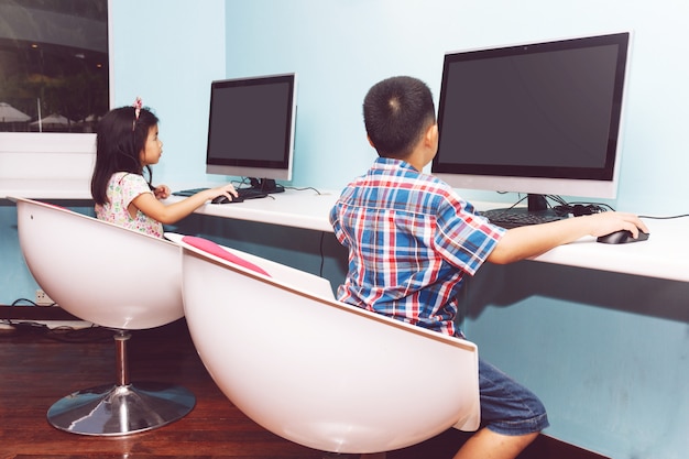 Niño y niña jugando con una computadora