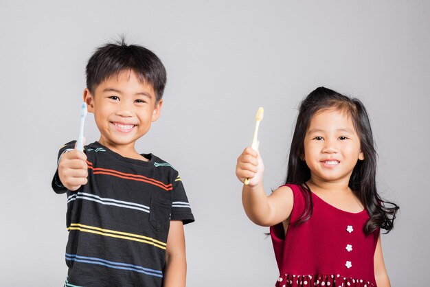 Niño y niña lindos muestran cepillarse los dientes y sonreír