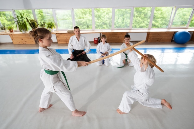 Niño y niña con lucha de aikido con palos