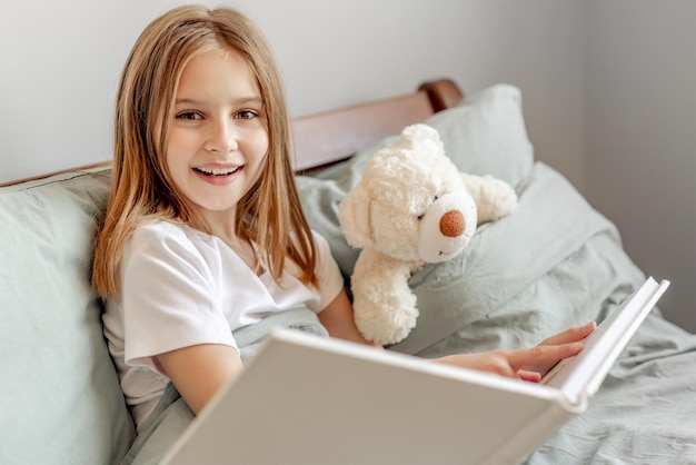 Niño niña con osito de peluche en la cama