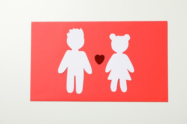 Niño y niña de papel y corazón sobre fondo blanco.