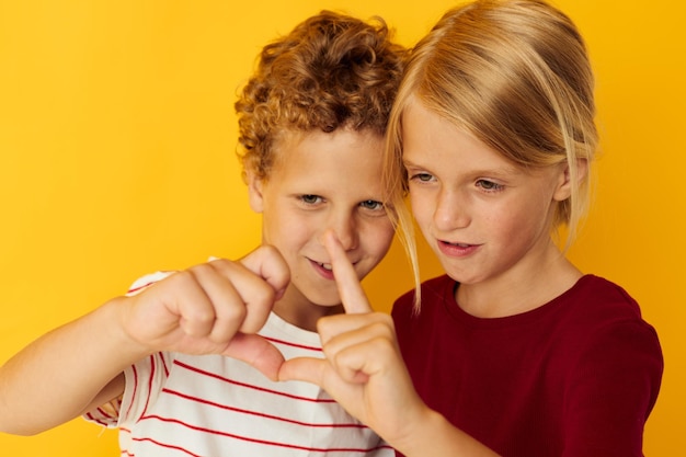 Niño y niña de pie uno al lado del otro posando emociones infantiles sobre fondo de color