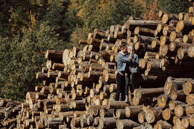 Niño y niña de pie sobre la pila de leña en el hermoso bosque de otoño colorido.