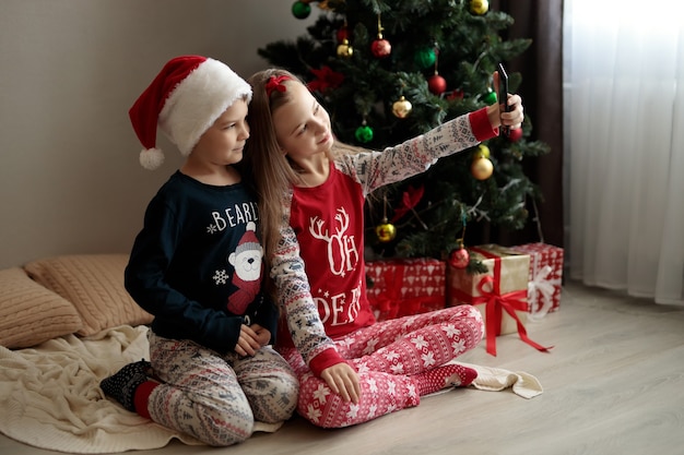 un niño y una niña en pijama de año nuevo los niños miran el teléfono