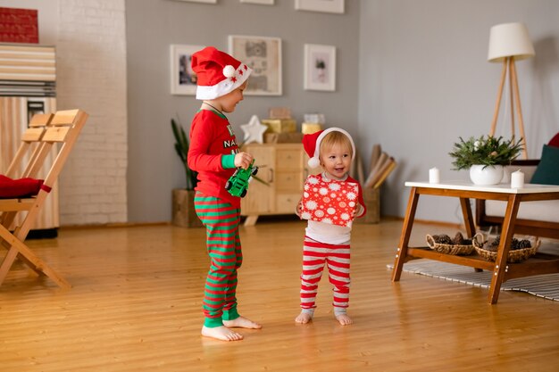 Niño y niña en pijamas acogedores y gorros de Santa Claus