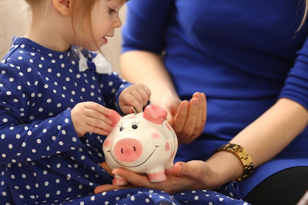 Niño niña poniendo dinero en la alcancía