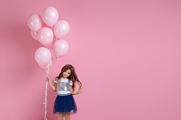 Niño niña posando con globos de aire rosa pastel